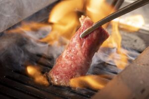 八王子で上質なお肉と厳選ワインが楽しめる焼肉店『焼肉カルロス』で肉を焼いているイメージ画像