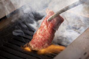 八王子駅4分のところにあるファミリーでも楽しめる焼肉店『焼肉カルロス』で肉を焼いているイメージ画像